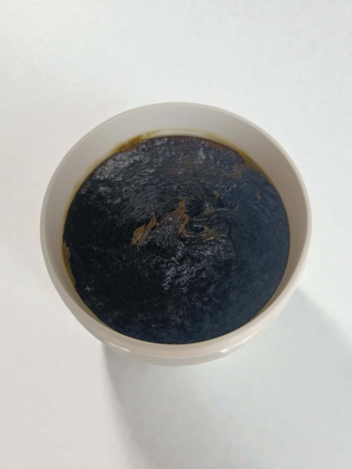 Bol de savon noir à l’huile d’olive traditionnel marocain, texture onctueuse et couleur sombre.